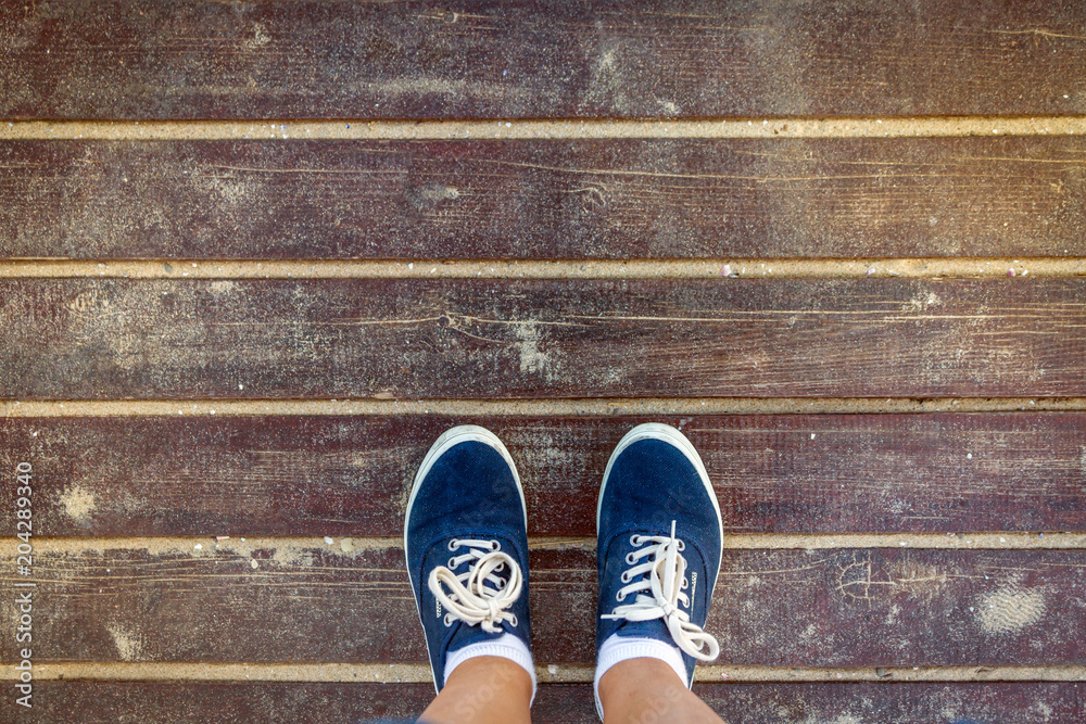 Blue sneakers standing on old sandy wooden floor. Top view.