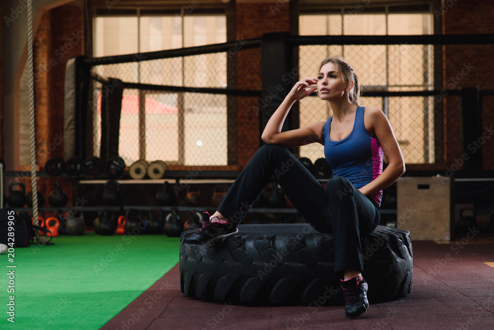 Obraz premium Girl sit at tire in gym