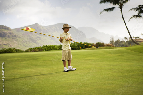 A boy holding a golf flag on the golf course photo