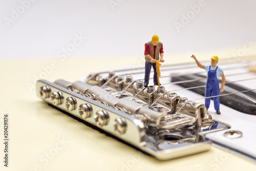 Fényképezés Miniature Workers Adjusting The Bridge Of An Electric Guitar