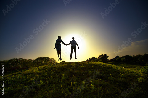 enthusiastically two people jumping on the hill