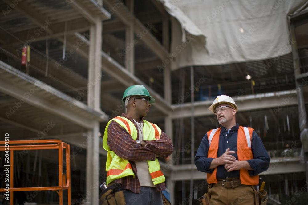 Two builders talking on a construction site Two builders talking on a construction site