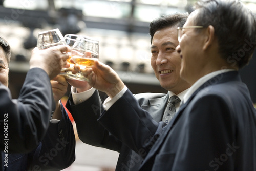 Mid-adult businessmen toasting a drink in a bar.