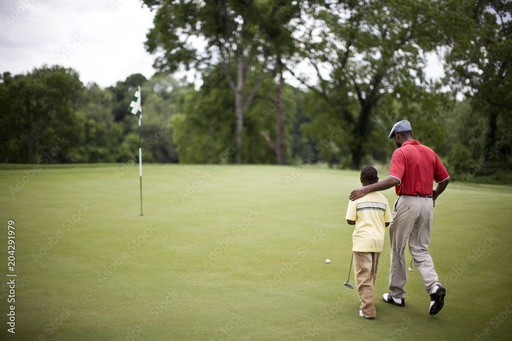 Father and son walking across a golf course Father and son walking across a golf course