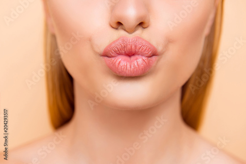 Air kiss for you. Close up cropped shot of femenine gorgeous charming adorable lady with nude natural full big pout lips isolated on beige background, perfection wellness wellbeing concept photo