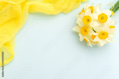 Fototapeta Naklejka Na Ścianę i Meble -  Daffodil bouquet with yellow textile decoration on blue pastel background with copy space.