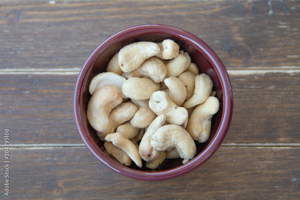 cashew nuts inside bowl on a wooden table viewed from above cashew nuts inside bowl on a wooden table viewed from above