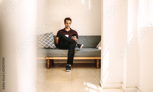 Man looking at mobile phone sitting at home