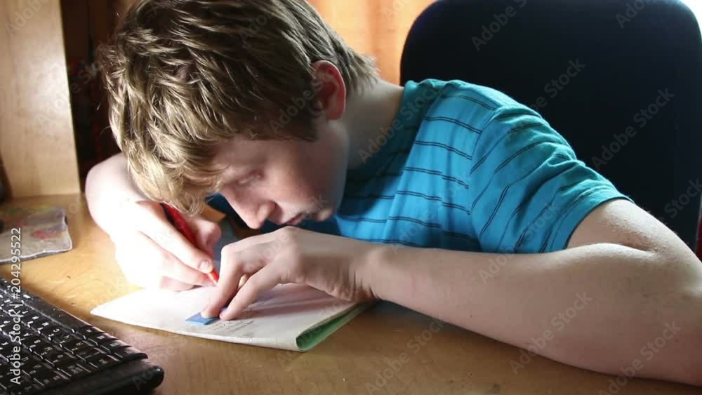 The boy writes in a notebook. A child is doing a school assignment at home.
The boy writes in a notebook. A child is doing a school assignment at home.