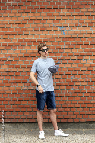 Portrait of attractive teenage boy standing in front of a brick wall.