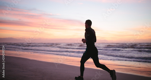 Healthy man jogging along the sea shore