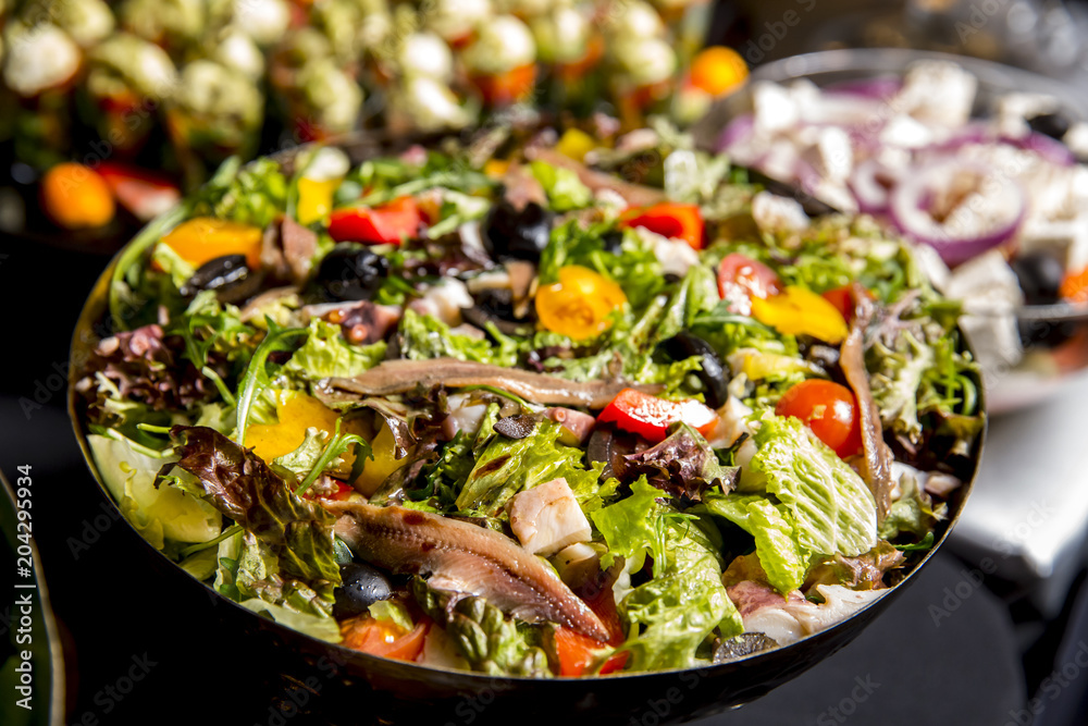 salad with anchovies lettuce, olives, tomatoes, mushrooms and onion on dark background