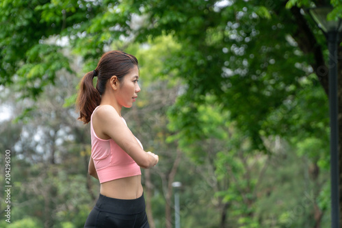 Beautiful young woman wearing orange sports warm up before exercise. Sporty young woman warming up before running in the public park. Sports and lifestyle concept.