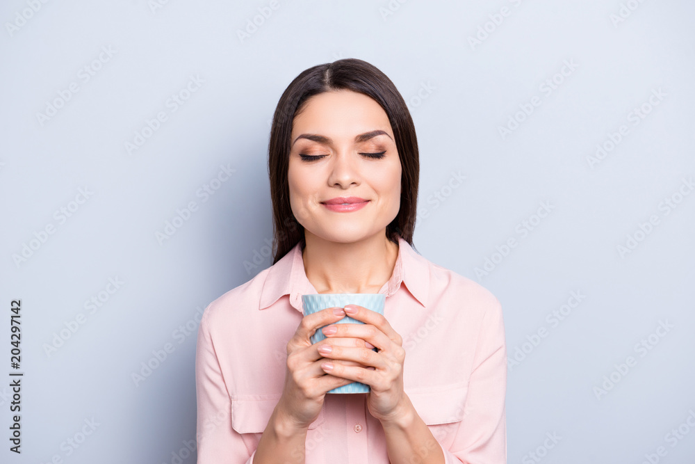 Portrait of lovely sweet, cute, nice, pretty, charming dreamy woman with close eyes holding mug with coffee in hands enjoying smell isolated on grey background Portrait of lovely sweet, cute, nice, pretty, charming dreamy woman with close eyes holding mug with coffee in hands enjoying smell isolated on grey background