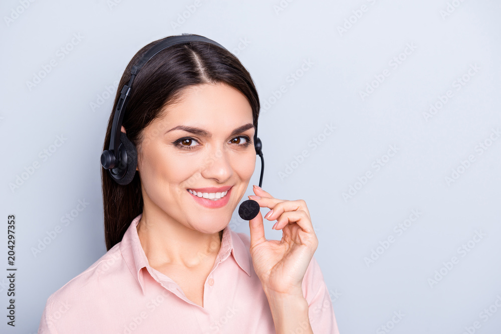 Portrait with copy space of cheerful pretty charming half turned woman in shirt with headset holding microphone looking at camera isolated on grey background advertisement concept Portrait with copy space of cheerful pretty charming half turned woman in shirt with headset holding microphone looking at camera isolated on grey background advertisement concept