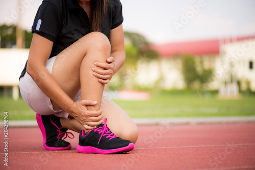 Ankle sprained. Young woman suffering from an ankle injury while exercising and running on Running Track. Healthcare and sport concept.