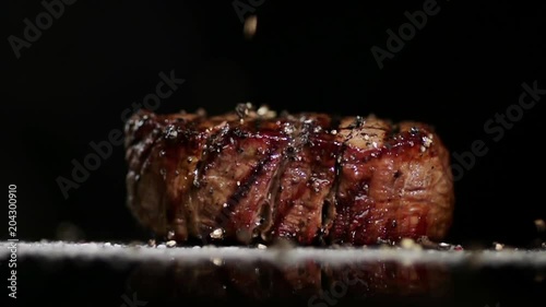 Spices are poured onto the steak and onto the surface.