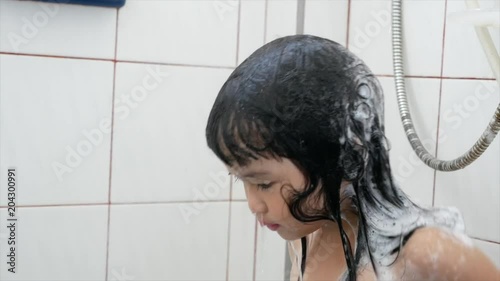 Asian children girl  washing hair in a bathroom, ms shot. photo