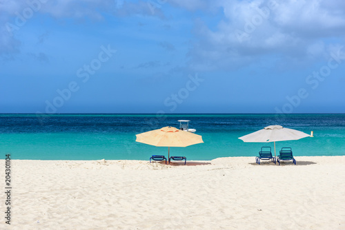 Parasols and sun beds on the shore of an idyllic caribbean beach