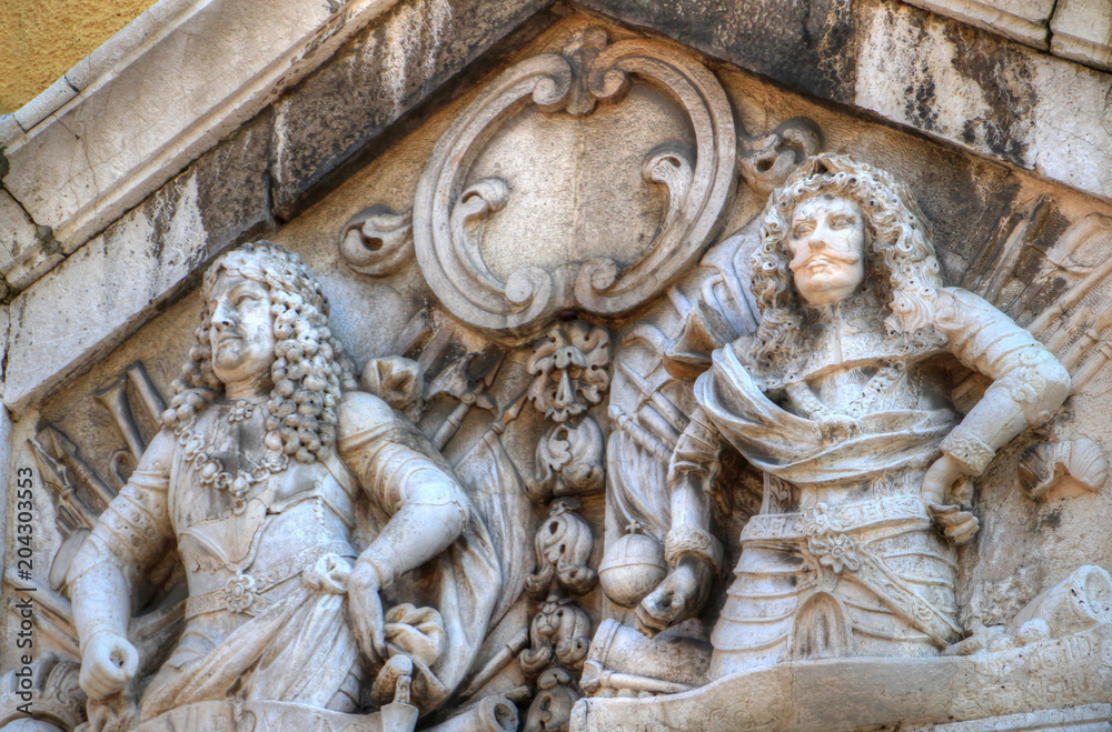 Closeup of Baroque era high reliefs of two long-haired men wearing plate armours on facade of Gradski toranj city clock tower a landmark building on main street Korzo in Rijeka Croatia Balkans Europe