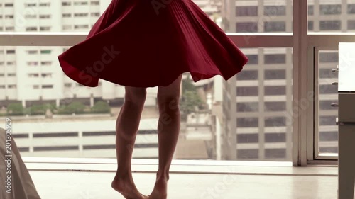 Young, beautiful woman in red dress turning around at home, super slow motion
