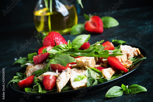 Salad with arugula, strawberries and chicken, dark background, selective focus