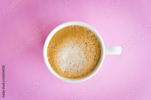 White cup of coffee on light pink  background