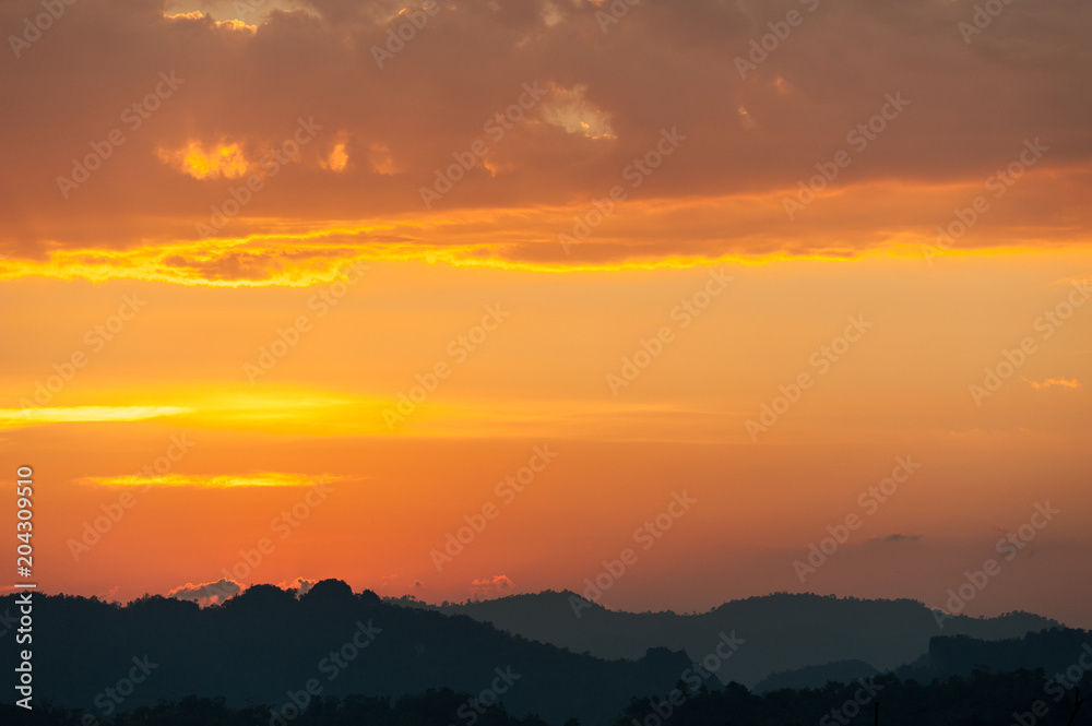 colorful dramatic sky with cloud at sunset. over silhouette mountains