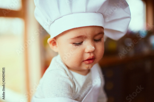 The small baby sits on the table in the kitchen