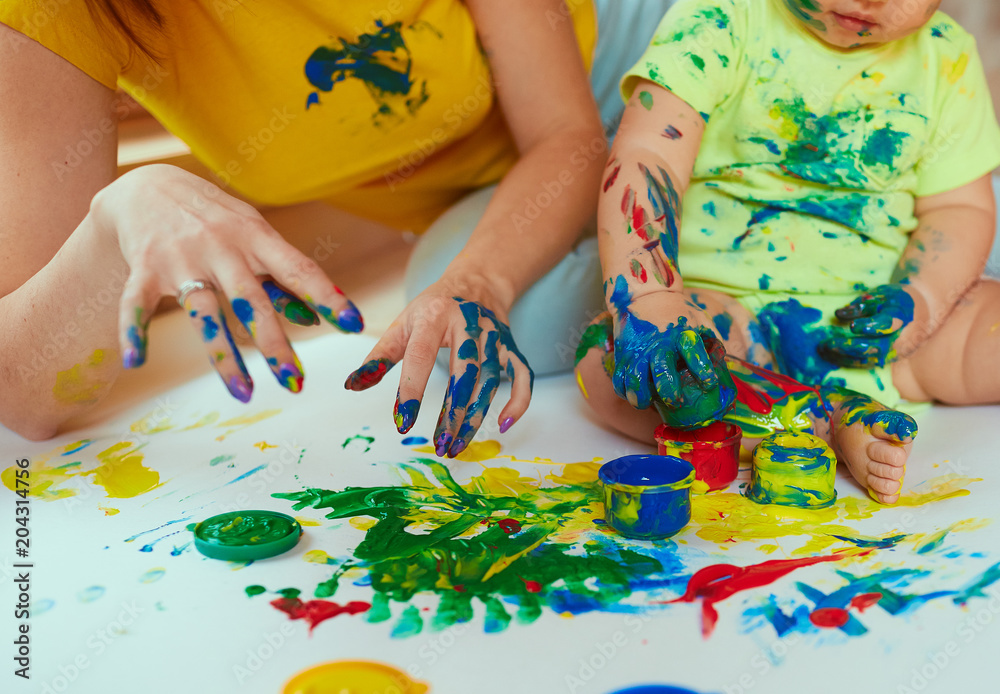 The mother with son painting a big paper by hands The mother with son painting a big paper by hands