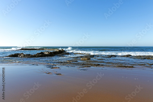 Wet Smooth Shoreline Beach Sand and Blue Coastal Skyline