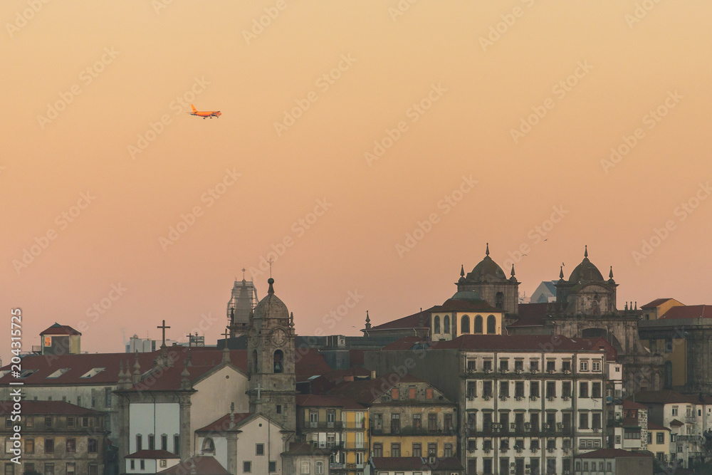 Close-up view of historic city of Porto, Portugal with plane flying over during sunrise time