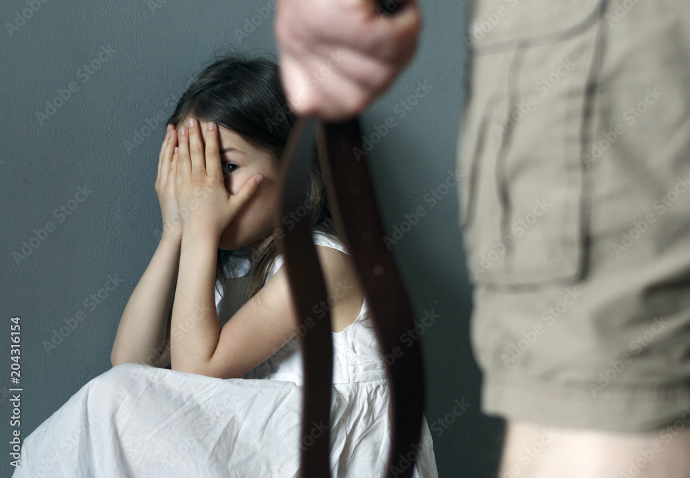 A man with a belt in his hand is going to punish a little girl A man with a belt in his hand is going to punish a little girl