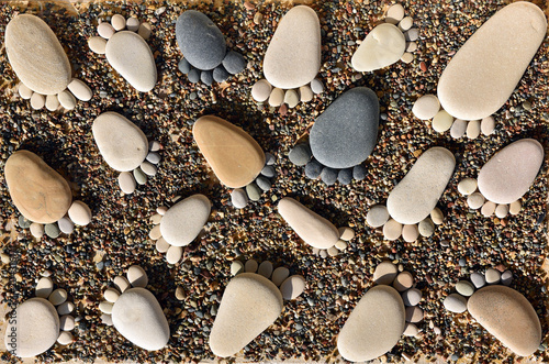 Pebble stones arranged like footprints on the beach photo