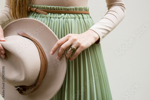 Hat, beige blouse and turqoise pleats skirt on light street backgraund.  Fashion and stylish concept.