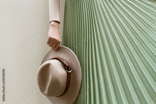 Hat, beige blouse and turqoise pleats skirt on light street backgraund.  Fashion and stylish concept. photo