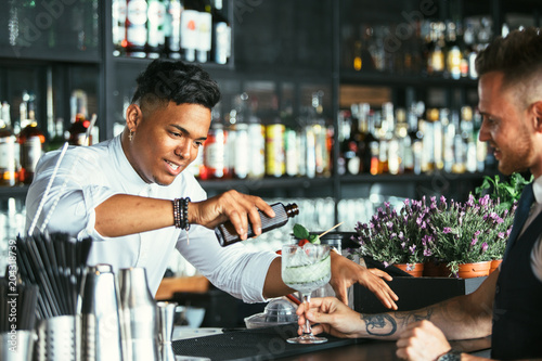 Bartender prepares a cocktail to a waiter photo