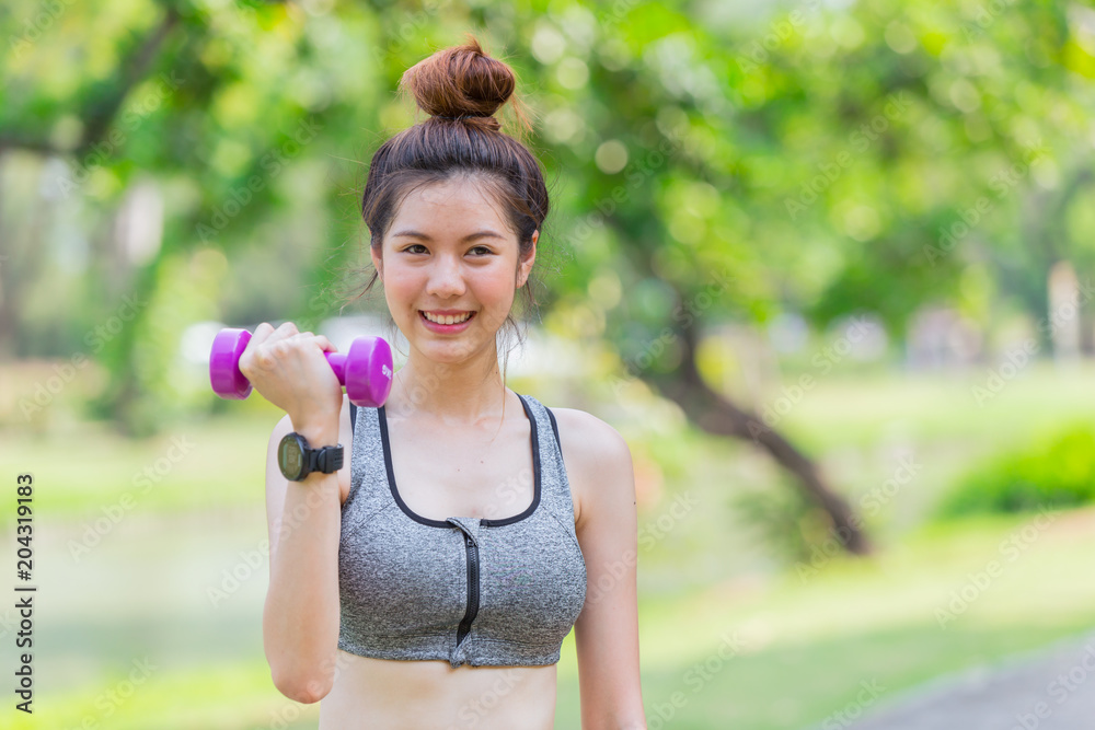 Asian cute teen slim and healthy enjoy Biceps workout with small drumbell in park with space for text Asian cute teen slim and healthy enjoy Biceps workout with small drumbell in park with space for text