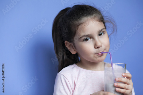 Happy little girl drinking a milk cocktail