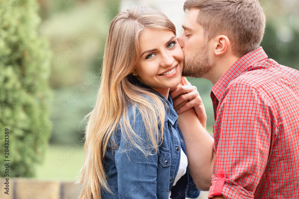 Young beautiful girl staring at camera while being kissed Young beautiful girl staring at camera while being kissed