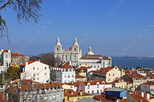 Sao Vicente de Fora Monastery, Alfama District orange rooftops and Tagus River estuary. Lisbon, Portugal.