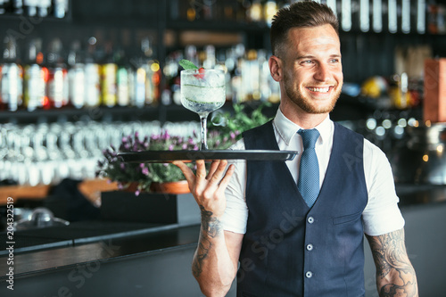 Smiling waiter ready to serve a cocktail photo