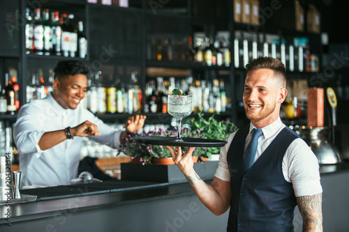 Smiling waiter with a cocktail photo