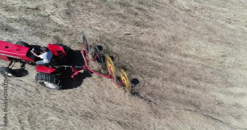 Closeup aerial view looking straight down on tractor with star wheel rake raking switchgrass in a field. photo