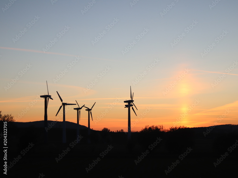 Obraz premium Wind power station in the sunset. Rotating blades of energy generators. Ecologically clean electricity. Modern technologies for the use of natural resources.