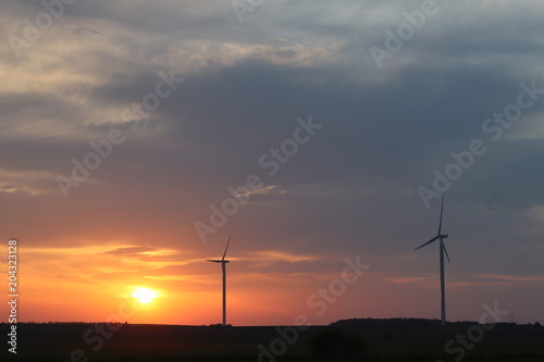 Wind power station in the sunset. Rotating blades of energy generators. Ecologically clean electricity. Modern technologies for the use of natural resources.