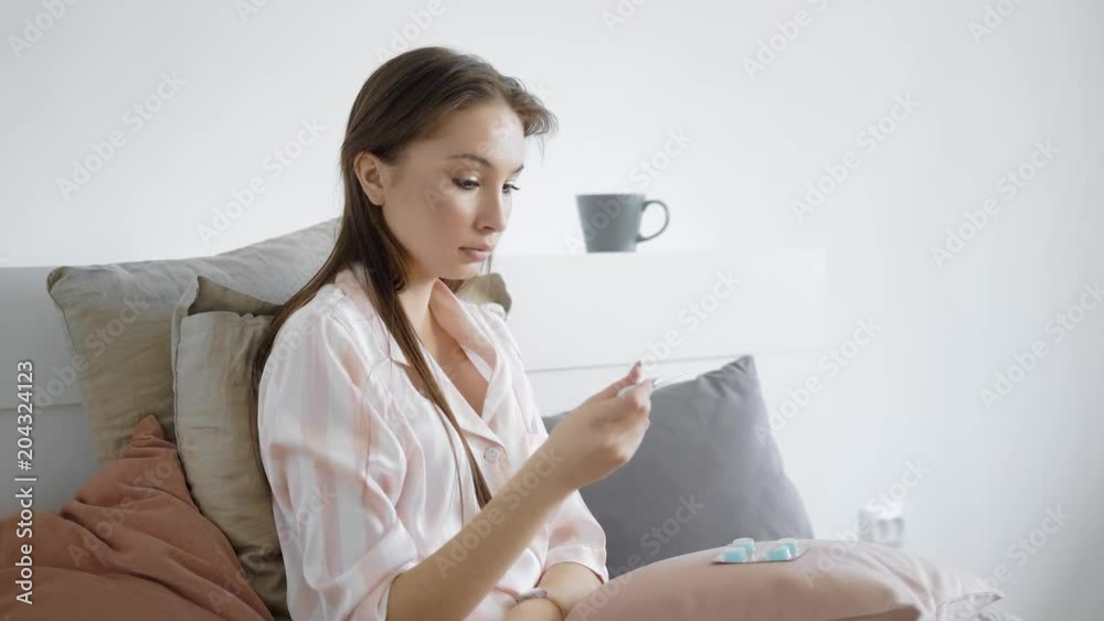Beautiful young woman is ill and sitting at home alone.
