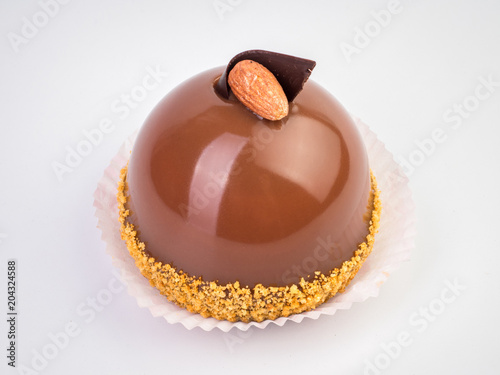 Mini mousse pastry dessert covered with chocolate velour and decorated with brown glaze and almond isolated on white background. Modern european cake. French cuisine.