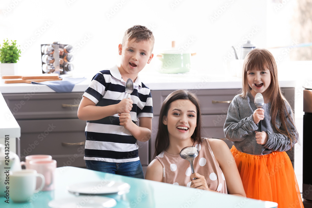 Happy family using utensils as microphone in kitchen