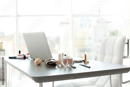 Makeup products for woman and laptop on table
